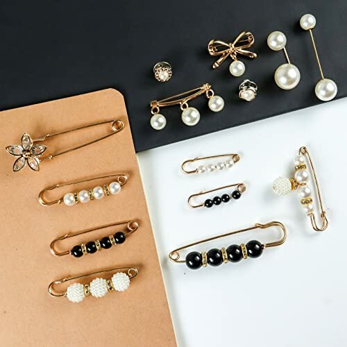 A collection of pearl and gold safety pin brooches and earrings on a black and beige background.